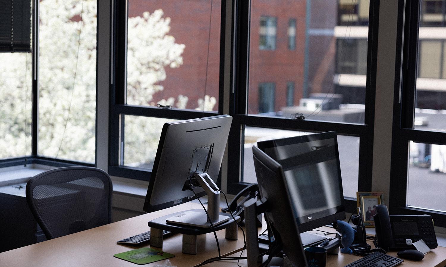 Two computers in a naturally lit office.