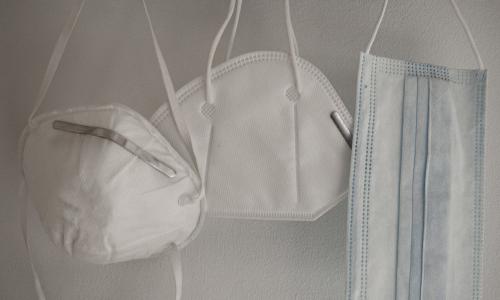 Three different face masks hanging on pegs.