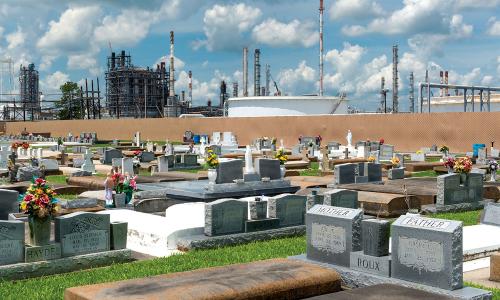 Cemetery in Cancer Alley, Louisiana, with refinery stacks in background