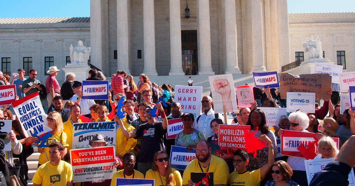 Protesters hold up anti-gerrymandering signs.